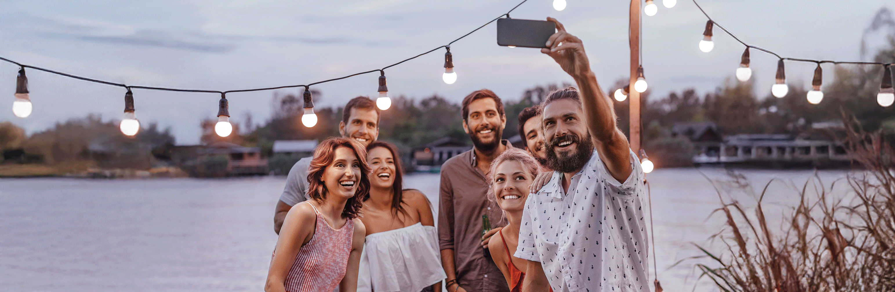 Freundesgruppe macht Selfie auf einem Steg am Wasser