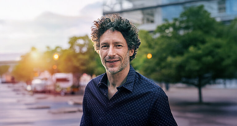 Mann mit grauen Locken blickt in die Kamera