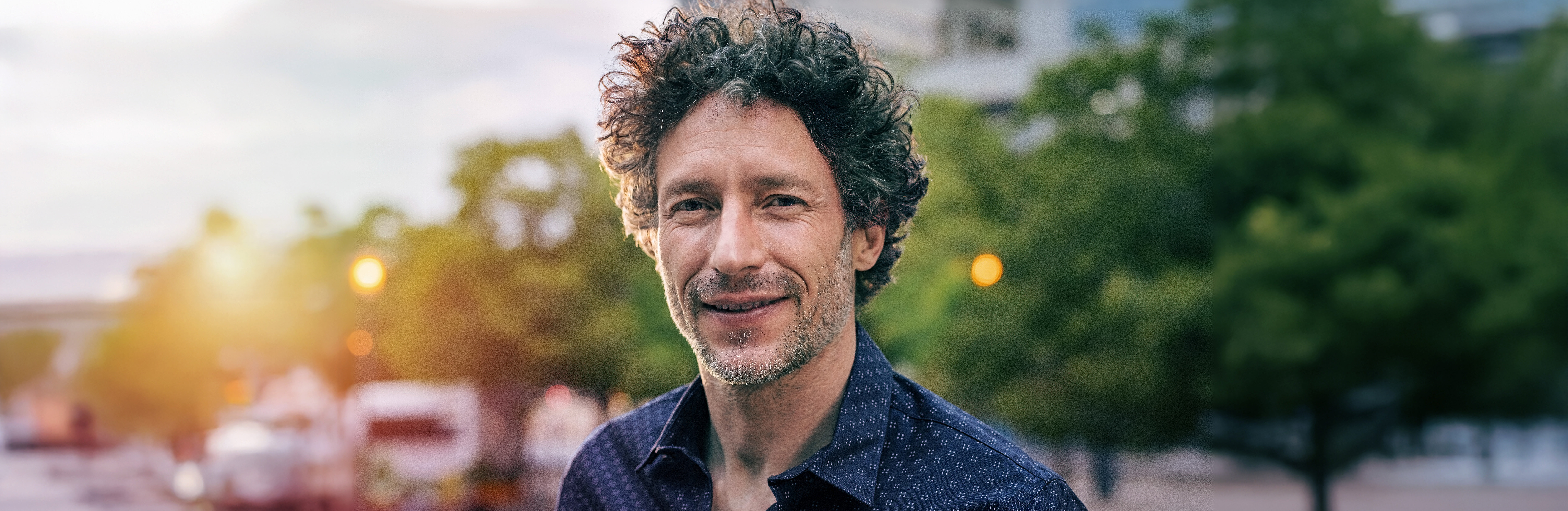 Mann mit grauen Locken blickt in die Kamera