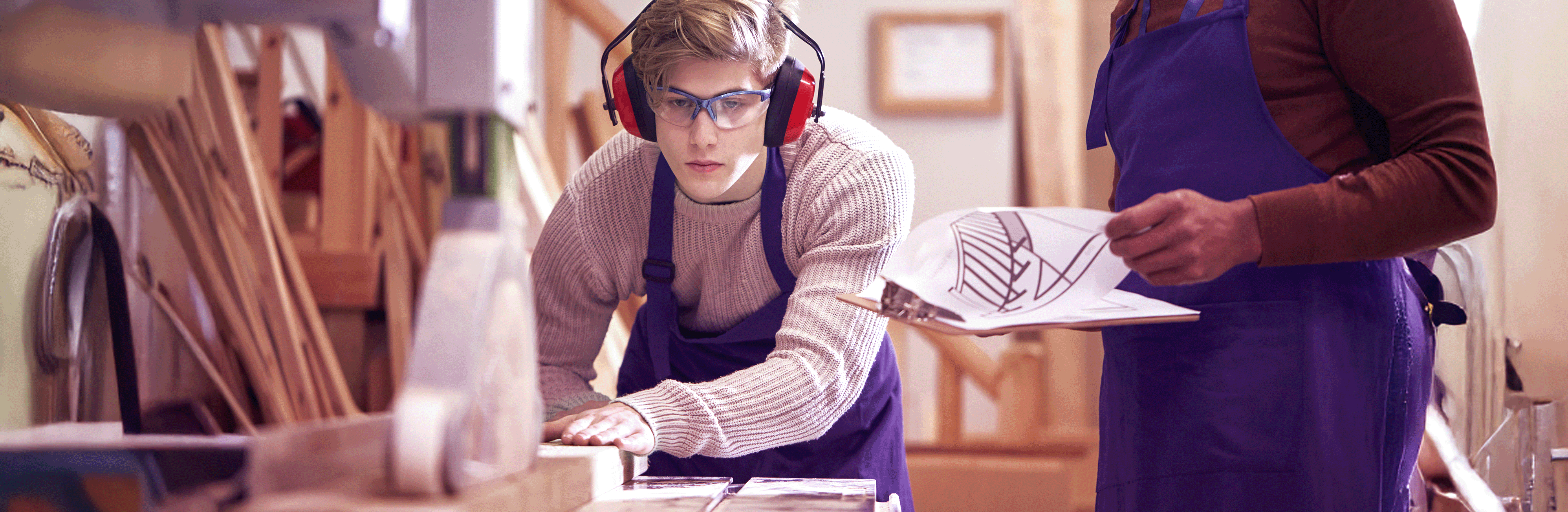 Azubi lernt Umgang an einer Tischler-Maschine